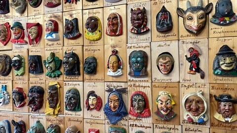 Kleine geschnitzte Masken hängen an einer Wand. Jedes Mäskle sieht anders aus. Der Besitzer kommt aus Bierlingen und ist Weltmeister im Miniaturmaskensammeln.