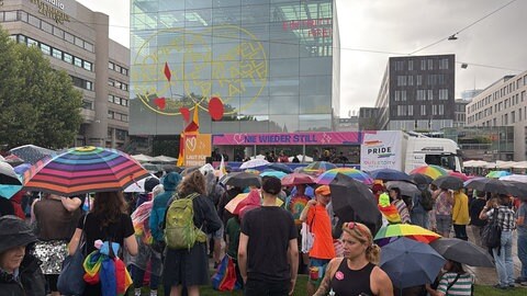 Viele Menschen stehen mit Regenschirmen bei der Kundgebung zum CSD Stuttgart 2025 auf der Richard‐von‐Weizsäcker‐Planie.