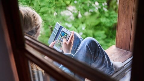 Ein Junge schaut auf ein Smartphone. Das Land Baden-Württemberg investiert Millionen in den Kinderschutz. Ministerpräsident Winfried Kretschmann will auch die sozialen Medien stärker regulieren.