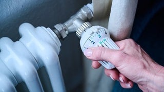 Heizung: Die Hand einer Frau stellt die Temperatur an einem Regler ein.