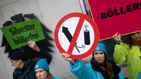 Frau hält Schild hoch und fordert das Verbot von Raketen und Böllern