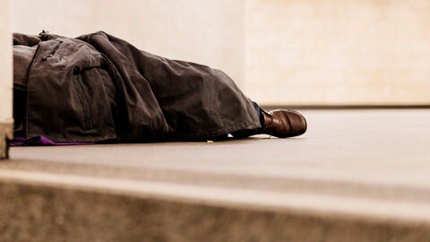 Das Symbolfoto zeigt einen Obdachlose, der improvisiert einer Decke schläft. In der Innenstadt von Koblenz ist die Leiche eines wohnungslosen Mannes gefunden worden, der vermutlich an Unterkühlung gestorben ist. 