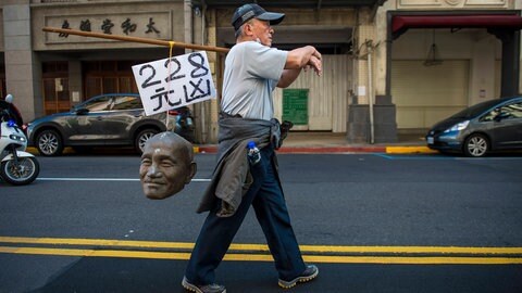 Ein Mann trägt am 28. Februar 2023 den von einer Statue Chiang Kai-sheks abgetrennten Kopf durch die Straßen Taipehs, um an das 228-Massaker von 1947 zu erinnern. Die Protestierenden fordern die Entfernung der Statuen und anderer Monumente des ehemaligen Diktators. 