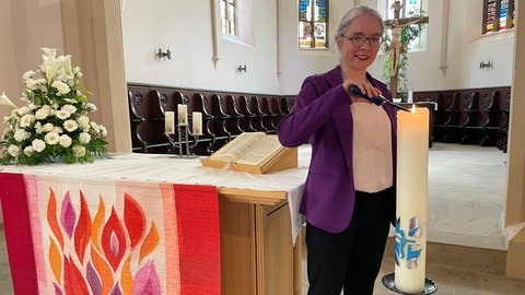 Die Pfarrerin Christine Siegl zündet vor der Sakristei in der evangelische Peter und Paul Kirche in Gönningen eine Kerze an.