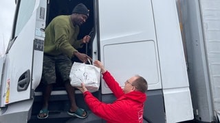 Thorsten Dossow von ver.di bringt dem Lkw-Fahrer Adam M. Essen vorbei.