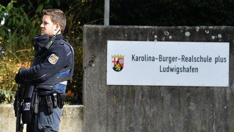 Ein Polizist steht vor der Karolina-Burger-Realschule in Ludwigshafen. Herrscht auch an anderen Schulen in der Stadt ein Klima der Angst?