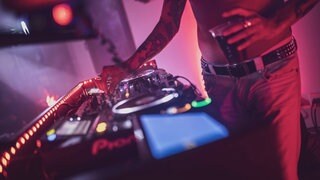 Ein Mann mit nacktem Oberkörper steht mit einem Drink in der Hand an einem DJ Pult: Die Polizei hat in Mainz eine illegale Party unter einer Autobahnbrücke aufgelöst. 