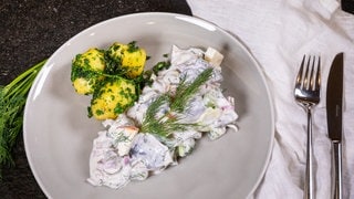 Der Heringssalat ist wie im Rezept beschrieben mit Pellkartoffeln auf einem Teller angerichtet.