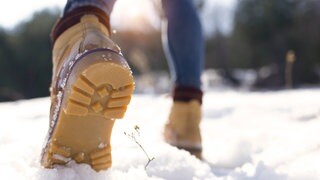 Person geht in hellen Stiefeln durch den Schnee: Schnee enthält viel Luft und wenn man drauftritt, drückt man die Luft raus. Aber warum knirscht das so?