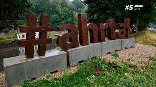 Neben einer Straße im Ahrtal wurde der Schriftzug "# ahrtal" aufgebaut.