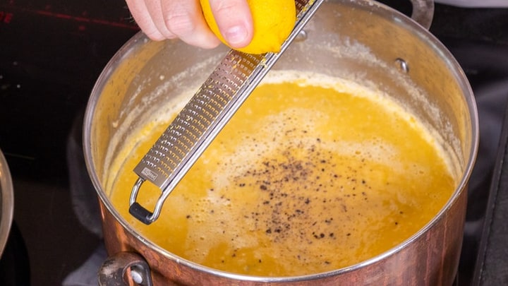 Über die fertige Kürbissuppe wird etwas Zitronenabrieb gegeben.
