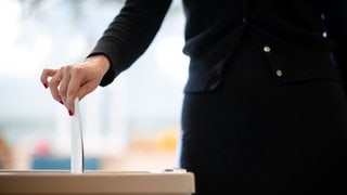 Eine Frau gibt ihren Stimmzettel ab