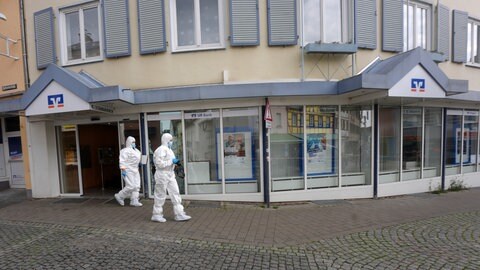 Polizeibeamte in weißer Schutzkleidung durchsuchen den Tatort in Sinzig.