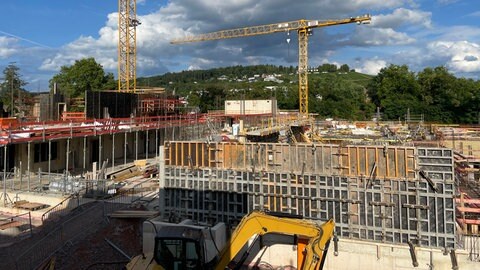 Der Rohbau auf der Baustelle an der Südallee mit zwei Baustellenkränen, im Hintergrund der Petrisberg
