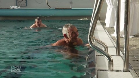 Zwei Männer schwimmen in einem Freibad auf privatem Gelände