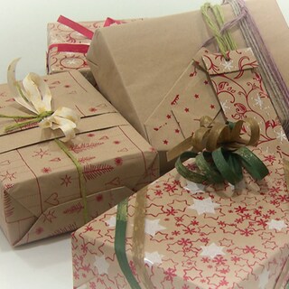 Mehrere Geschenke sind in bedrucktes Geschenkpapier eingepackt und mit Bändern und Schleifen geschmückt.