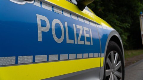 Ein Polizeiauto steht am Waldrand. In Sohren im Hunsrück ermittelt die Polizei nachdem dort ein Mann überfahren und getötet wurde.