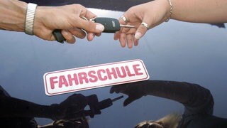 Ein Fahrlehrer überreicht seiner Fahrschülerin den Schlüssel zum Fahrzeug (Symbol): In einer Fahrschule in Brackenheim sollen falsche, bezahlte Prüflinge die Theorieprüfung absolviert haben.