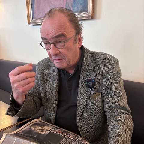 Schriftsteller Robert Menasse in einem Kaffeehaus mit einer Zeitung