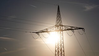 Ein Strommast wird von der Sonne angestrahlt. Verursachen hohe Temperaturen Stromausfälle?