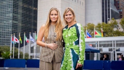 Königin Maxima und Prinzessin Amalia posieren in New York City vor dem UN Hauptquartier. Maxima trägt ein grün-blaues Kleid und Amalia ein gestreiftes Kostüm.