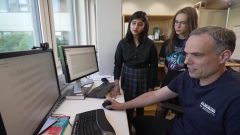 Die beiden Schülerinnen, die das Virus für ihr Jugend forscht Projekt entdeckt haben, sitzen mit einem Wissenschaftler vom EMBL Heidelberg vor einem Computer.