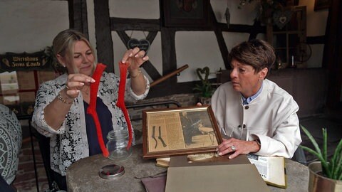 Silke Becker aus Pfinztal und Sonja Faber-Schrecklein sitzen am Tisch und schauen ein Fotoalbum an.