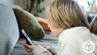 Ein Junge liegt auf einer Couch. Auf dem Bauch liegend schaut er auf ein Handy. Rechts das SWR Logo für Leichte Sprache.