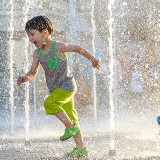 Kinder rennen durch Wasserfontänen