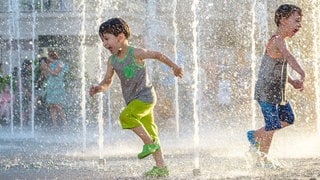 Kinder rennen durch Wasserfontänen