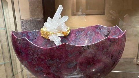 Im Gewölbekeller des Museums steht eine dunkelrosane große zerbrechliche Schale verziert mit Bergkristallen.
