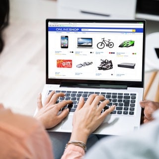 Frau von hinten vor Laptop mit Online-Shop. Wie sicher ist das Bezahlen per Vorkasse?
