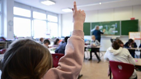 Ein Kind meldet sich in einer Grundschulklasse