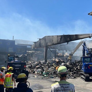 Auf dem Großmarkt in Stuttgart Wangen wird nach dem Feuer Schutt weggebaggert und es qualmt noch. Die Nachlöscharbeiten werden wohl noch bis in den Abend dauern.