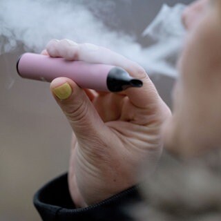 Eine Frau konsumiert eine E-Zigarette. Die Landesregierung will mehr Einschränkungen für Raucher im öffentlichen Bereich. Darunter fallen auch Vapes und E-Zigaretten. Ein Bürgerforum soll Empfehlungen liefern.