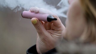 Eine Frau konsumiert eine E-Zigarette. Die Landesregierung will mehr Einschränkungen für Raucher im öffentlichen Bereich. Darunter fallen auch Vapes und E-Zigaretten. Ein Bürgerforum soll Empfehlungen liefern.