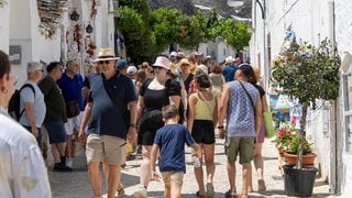 Touristen in Alberobello schauen sich die traditionallen Trulli Häuser an.