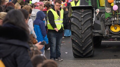 Mitarbeiter eines Sicherheitsdienstes sichern beim Koblenzer Rosenmontagszug 2024 die Räder der Traktoren ab. Auch 2026 hat die Sicherheit der Karnevalisten oberste Priorität. 